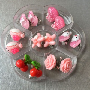 Set di 7 orecchini a clip per bambini in rosa, in un divisorio trasparente con sfondo bianco
