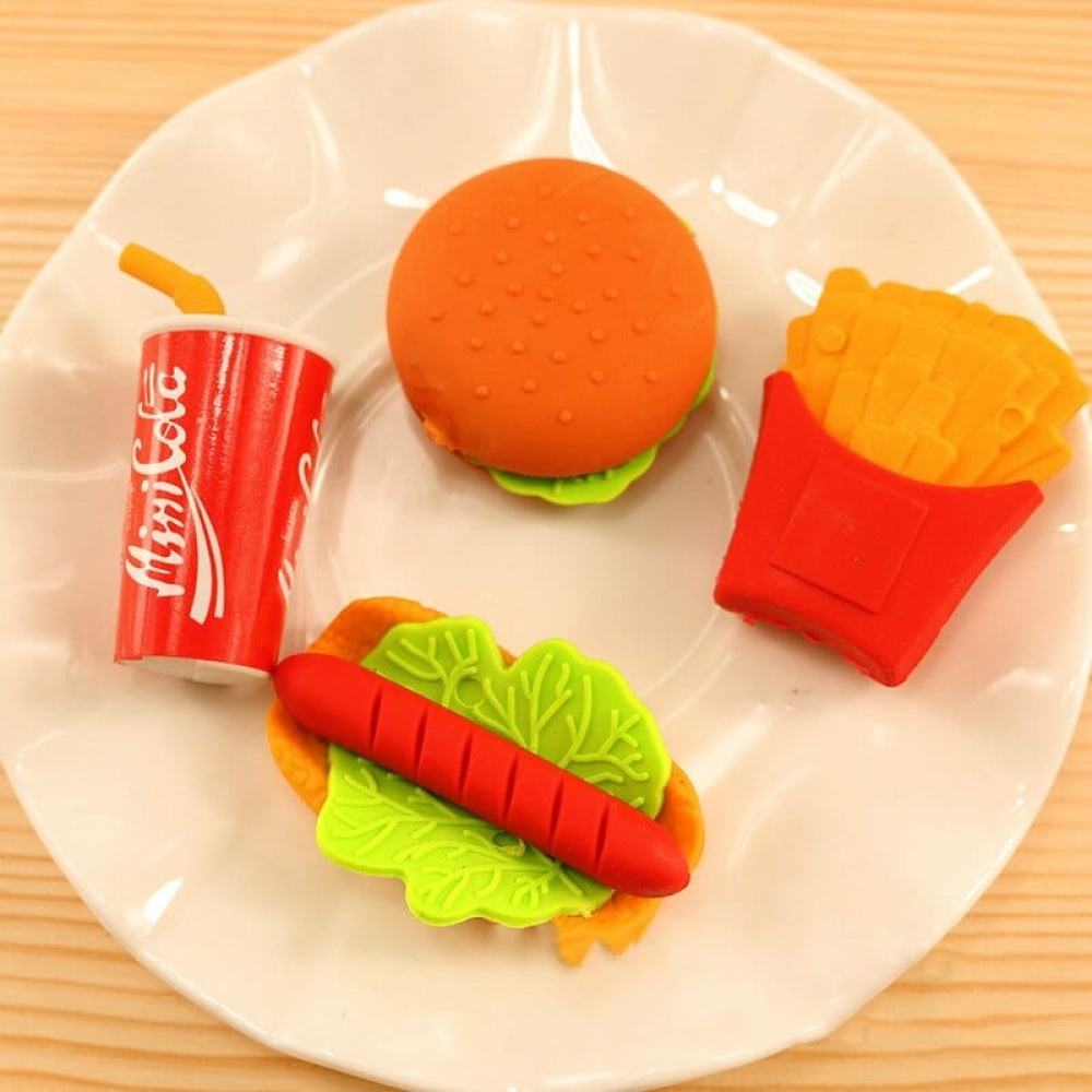 3 pezzi di gomma a forma di cibo per bambini in un piatto bianco su un tavolo di legno