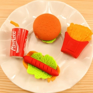 3 pezzi di gomma a forma di cibo per bambini in un piatto bianco su un tavolo di legno