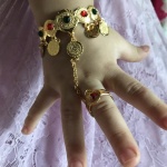 Bracciale e anello collegati da una catena per una bambina sulla mano di una bambina con una gonna bianca