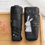 Mini ombrello tascabile per bambini con coniglio bianco su un ombrello nero su un tavolo di legno