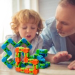 Puzzle in plastica verde, blu e arancione per bambini con bambino e padre in una stanza per giocare su un tavolo
