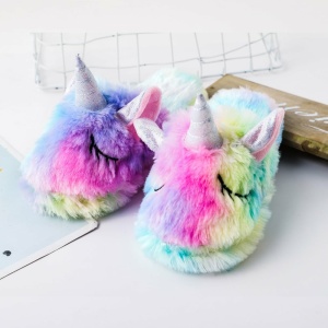 Pantofole da unicorno arcobaleno per bambini su un tavolo bianco con morbida pelliccia