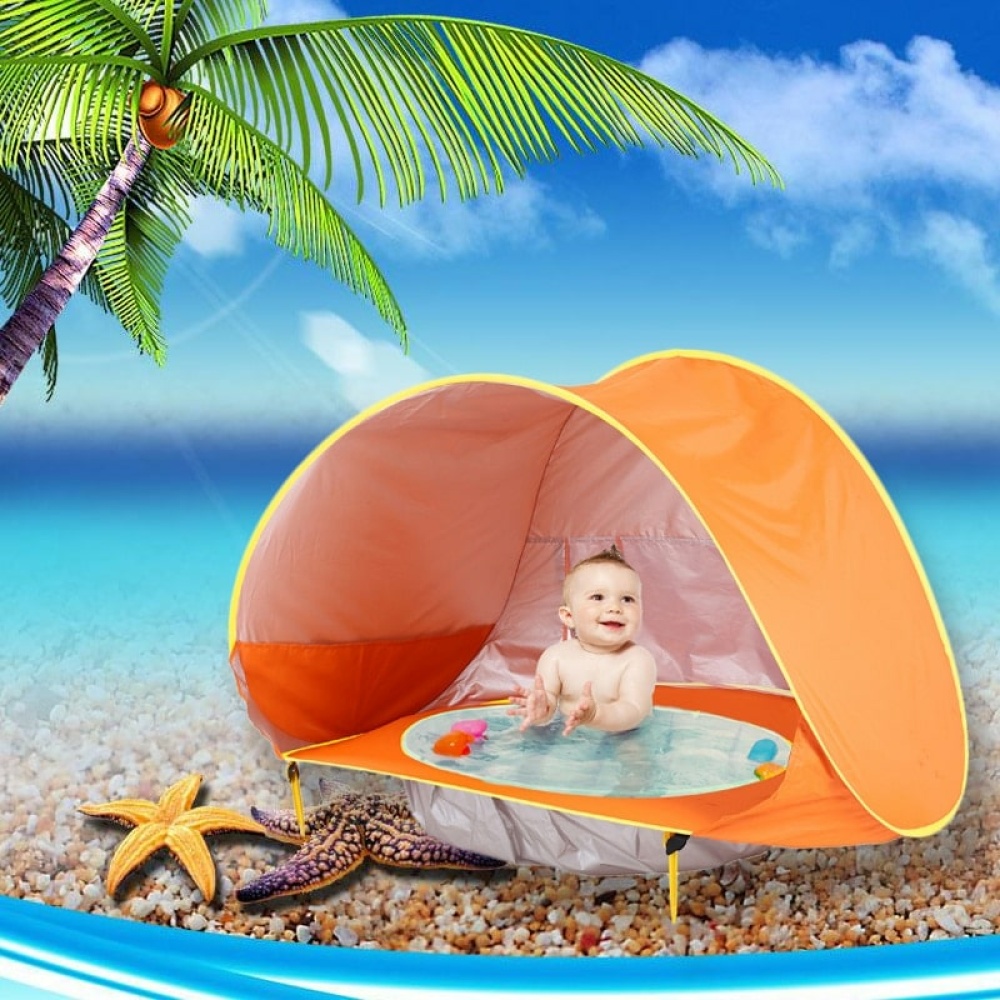Tepee da spiaggia per bambini arancione, con bambino all'interno, su una spiaggia con il mare e una palma