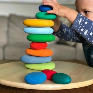 giocattoli di pietra colorata da impilare per bambini su un piatto di legno
