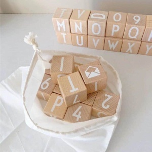 Un alfabeto giocattolo di legno da impilare in un sacchetto bianco su un tavolo bianco