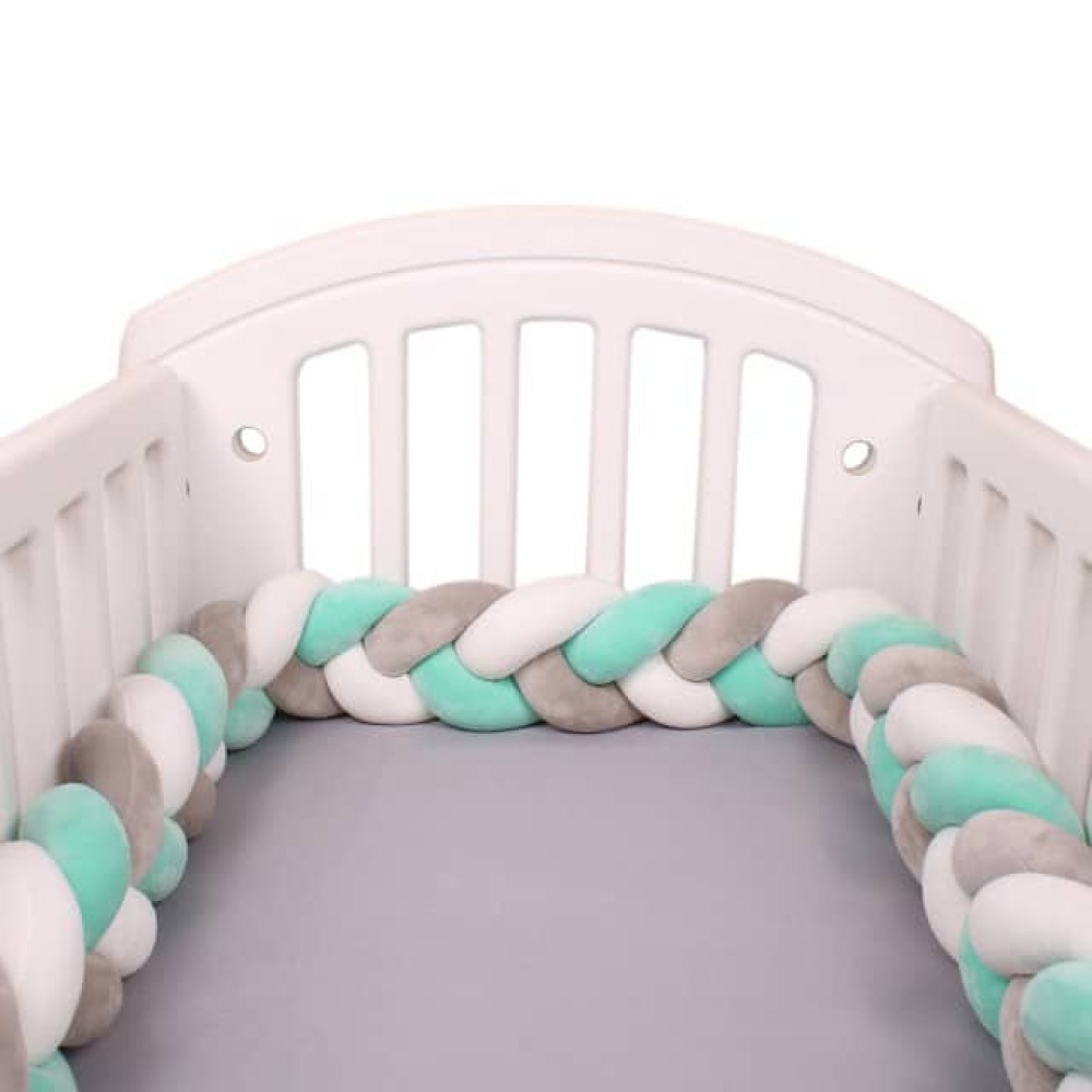 Paraurti intrecciato verde bianco grigio Cuscino paracolpi intrecciato grigio-bianco-verde in un lettino bianco con lenzuola grigie