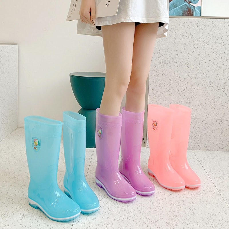 Stivali da pioggia in gomma trasparente blu, rosa e arancione ai piedi di una ragazza