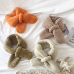 Sciarpa di lana calda per bambini su un letto bianco con cappotto
