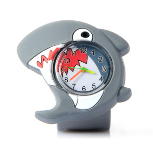 Un orologio per bambini in plastica con un simpatico squalo, con un quadrante in vetro al centro, lancette colorate all'interno e i denti dello squalo stampati.