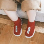vediamo le gambe di un bambino seduto che indossa calzini rossi con un'etichetta bianca