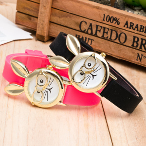 su un tavolo di legno, due orologi dello stesso modello, vicino a una cassa di legno, uno rosa e uno nero, con un simpatico coniglietto con gli occhiali sul quadrante