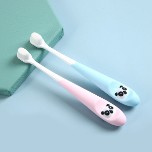 2 spazzolini da denti per bambini di colore rosa e blu appoggiati su un supporto verde