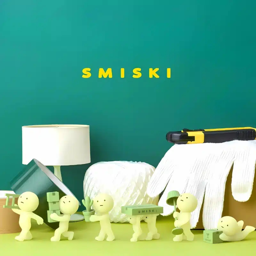 Figurines Smiski collection Moving, mettant en scène de petites figurines phosphorescentes effectuant des tâches de déménagement, avec des cartons, des plantes et divers objets.